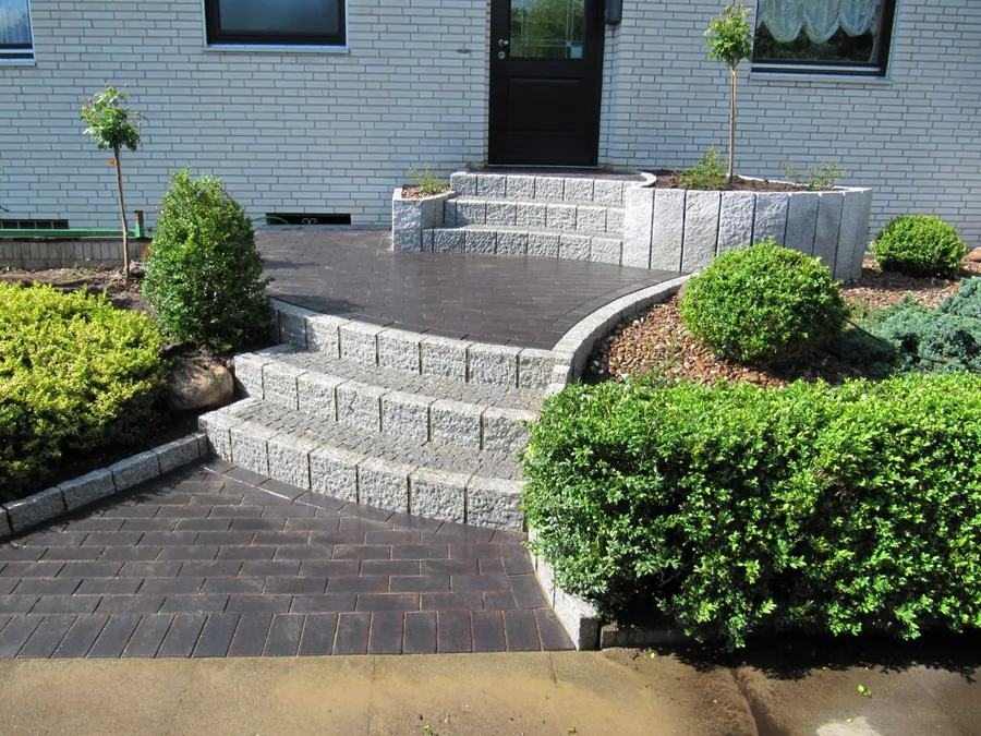 Eingangstreppe aus Granit-Blockstufen mit Klinkerweg und Buchsbaum