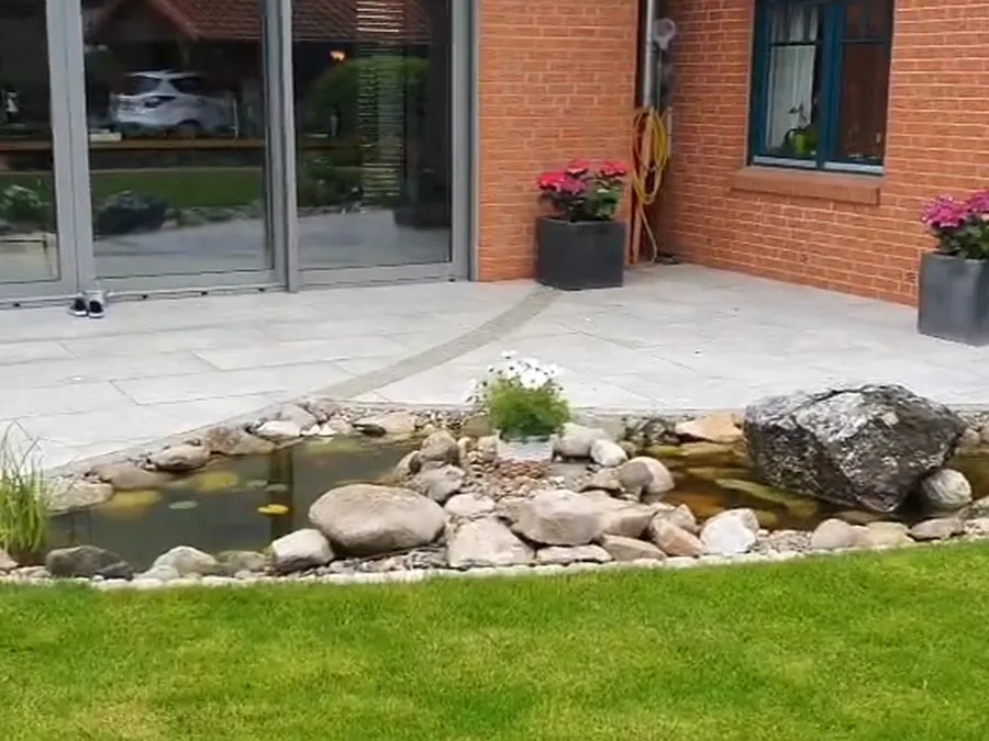 Gartenteich mit Natursteineinfassung, Bepflanzung und angrenzendem Rasen