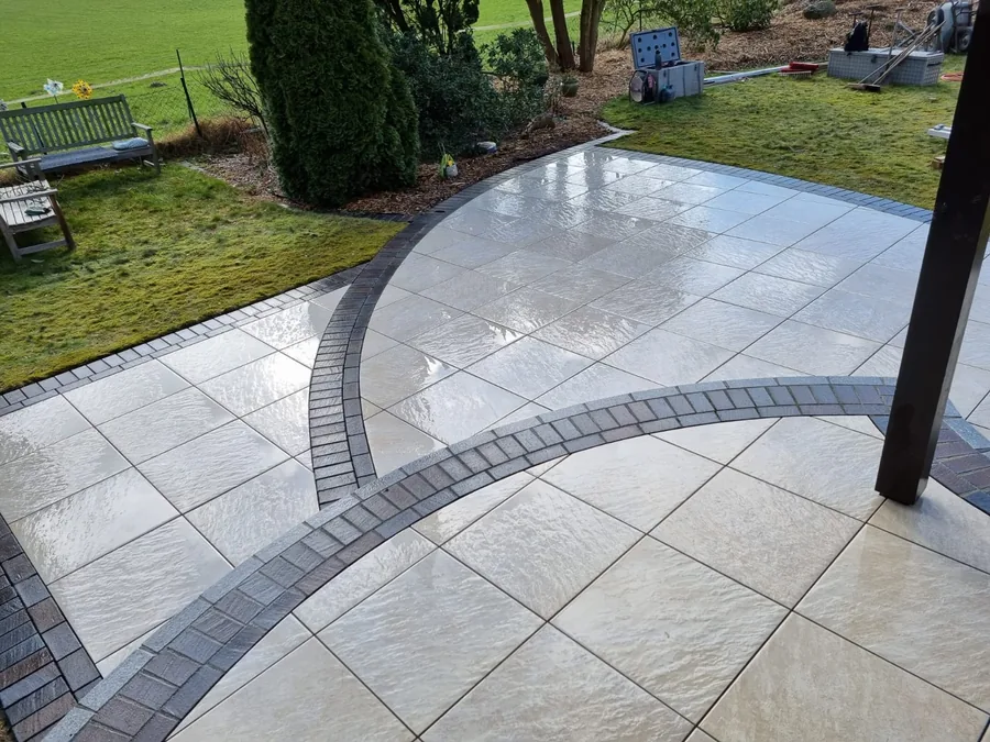 Terrasse aus großformatigen Platten mit dunkler, geschwungener Bordüre