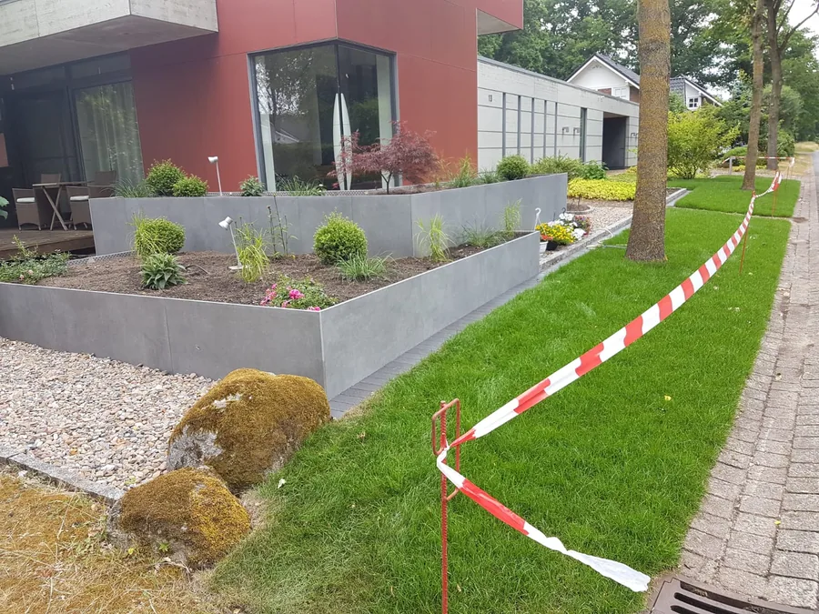 Hochbeet mit Keramikplatten verkleidet, davor Rasen und Kiesstreifen