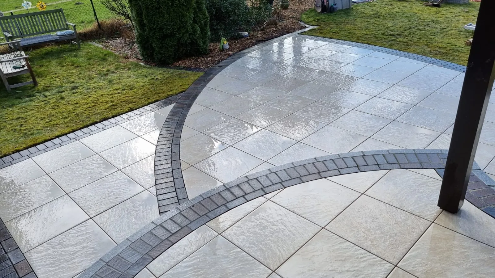 Terrasse aus großformatigen Platten mit dunkler, geschwungener Bordüre