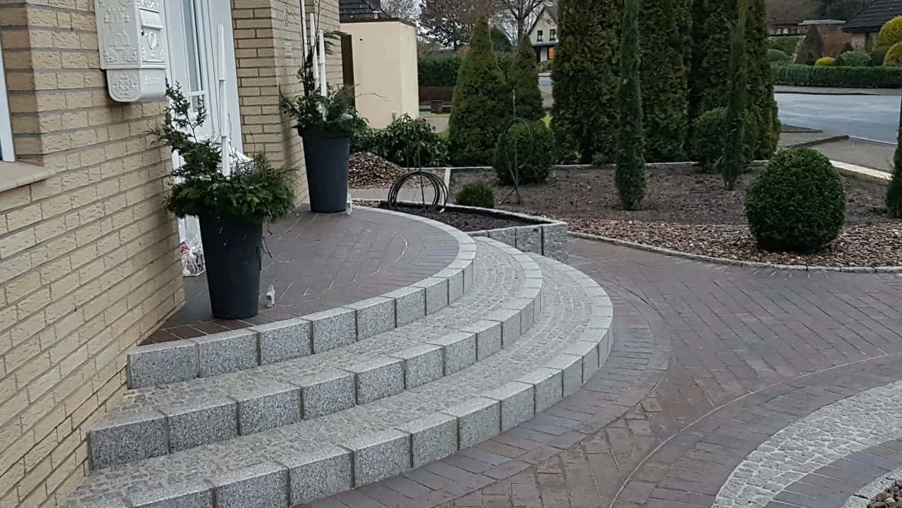 Hauszugang mit Granittreppe, geschwungenem Weg und Bepflanzung