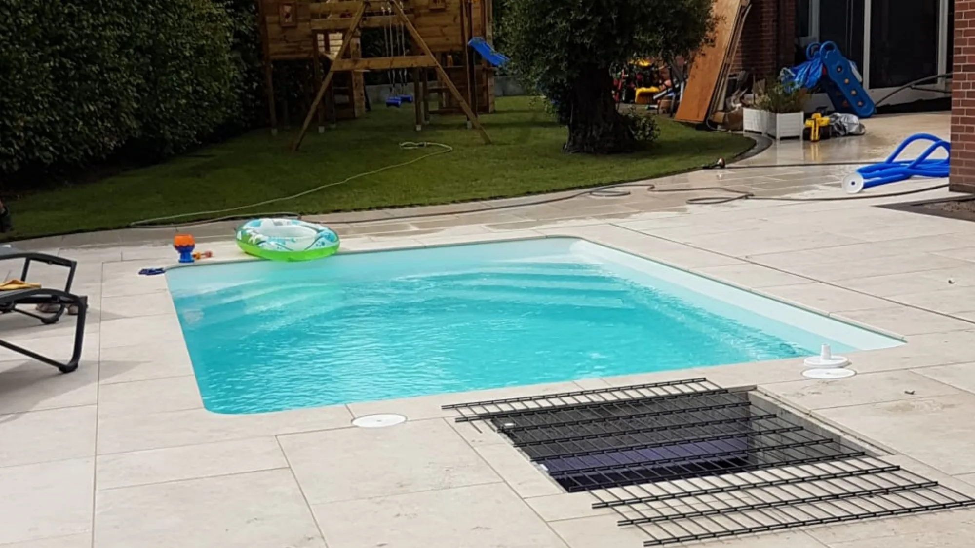 Rechteckiges Schwimmbecken mit Plattenumrandung und angrenzender Rasenfläche