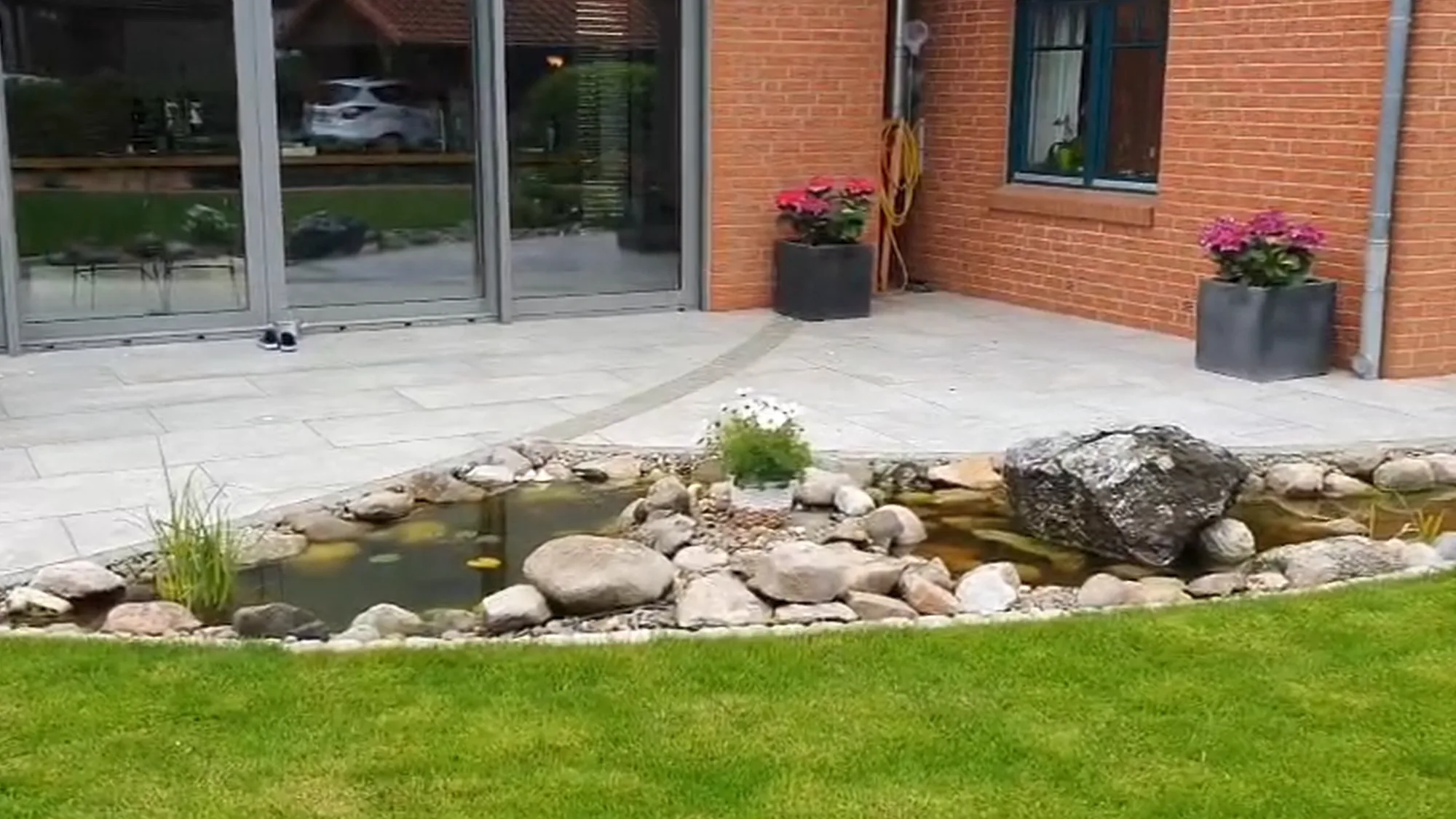 Gartenteich mit Natursteineinfassung, Bepflanzung und angrenzendem Rasen