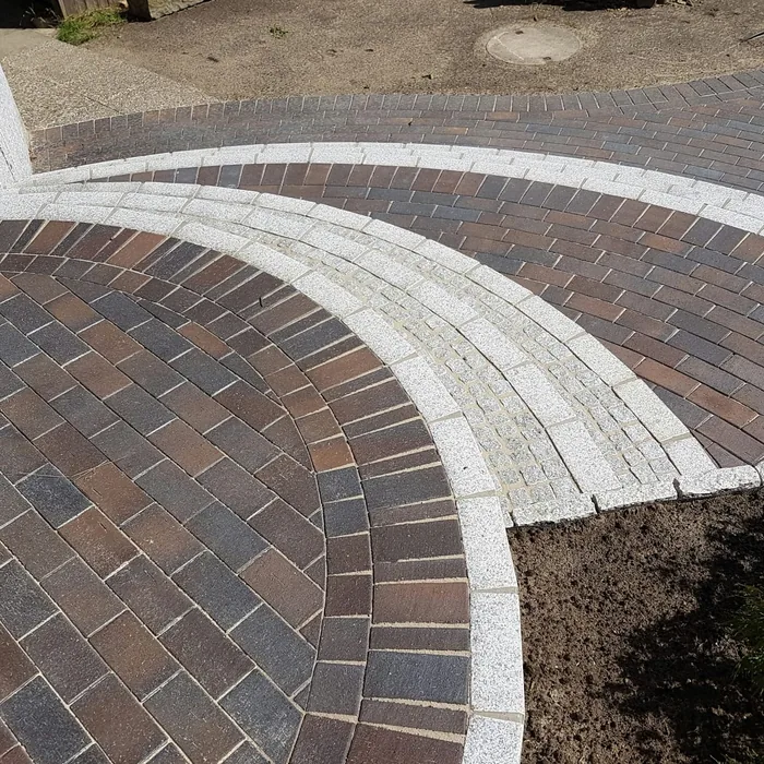 Im Bogen verlegtes Klinkerpflaster mit heller Granit-Randeinfassung