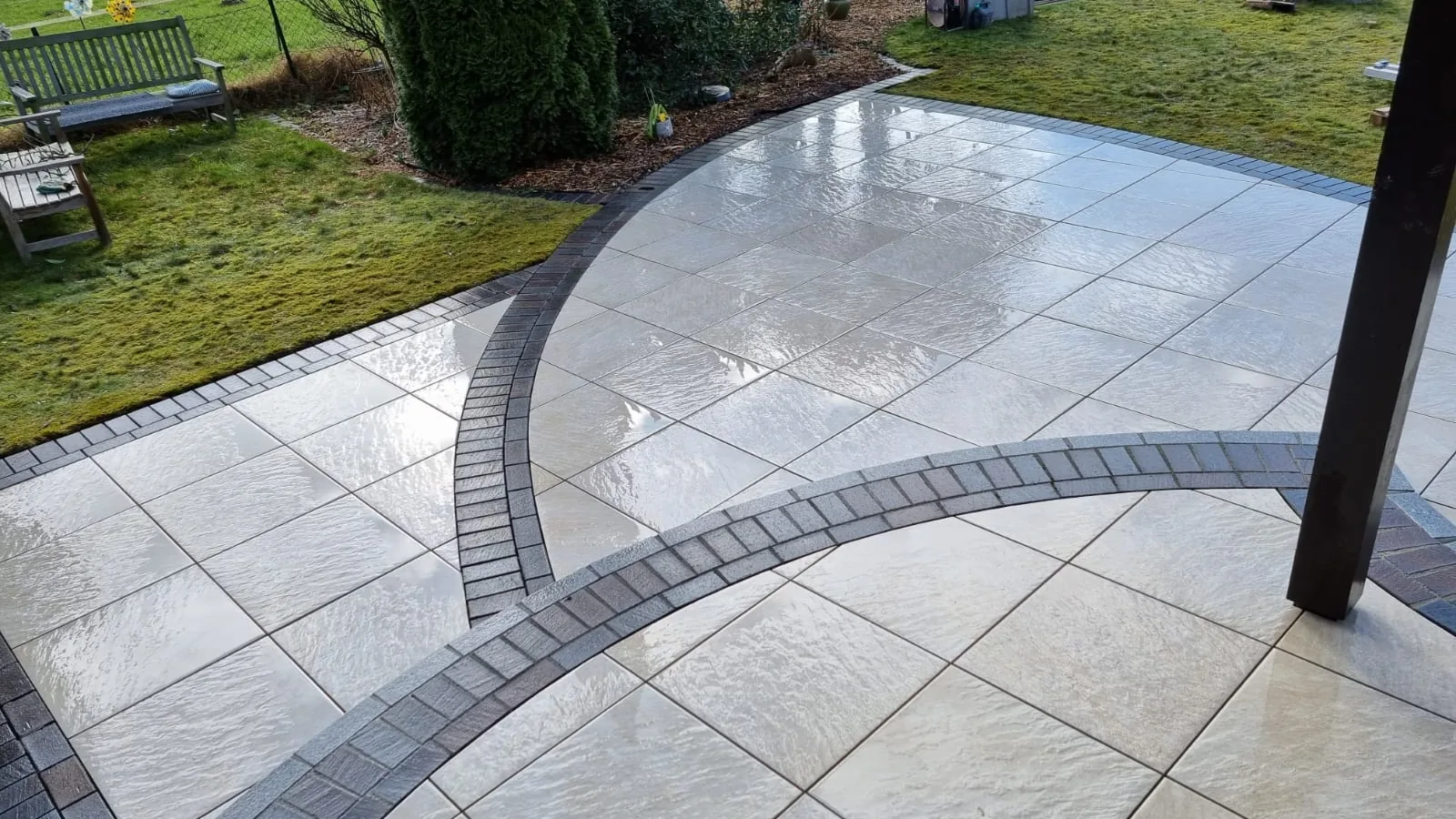 Terrasse aus großformatigen Platten mit dunkler, geschwungener Bordüre